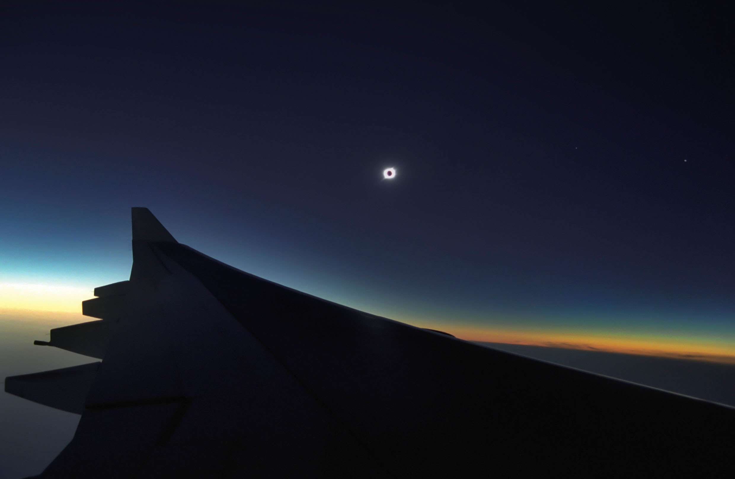 Eclipse total de Sol con su corona sobre la línea del atardecer, fotografiado en vuelo